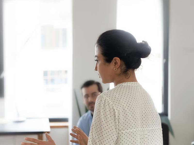 Woman speaking to colleagues in a bright, modern office setting