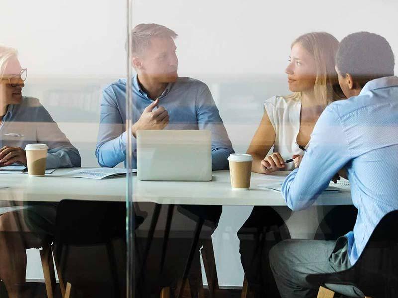 Group of professionals having a meeting around a table in a glass-walled office