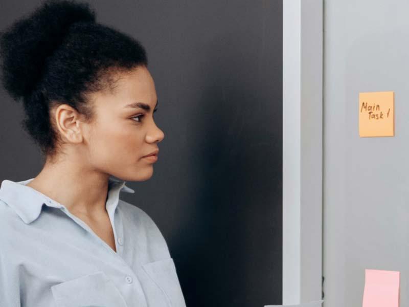 Focused woman looking at sticky notes on a board