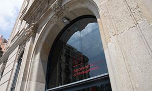 Main entrance of UPF Barcelona School of Management, with logo on the glass and reflection of nearby buildings.