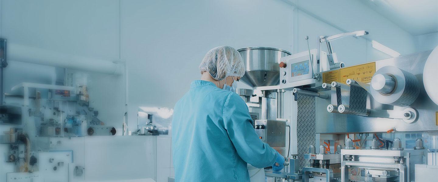 Technician operating machinery in a pharmaceutical laboratory.